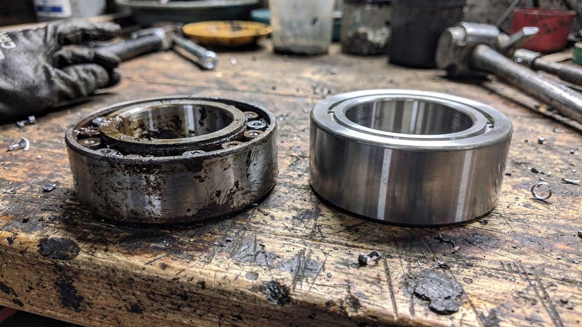 A failed wheel bearing lying beside its new replacement on a workshop bench